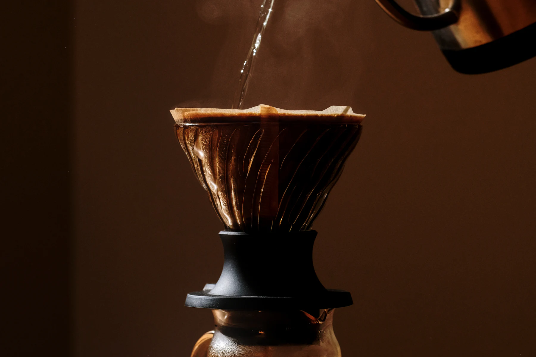 Coffee being poured into a pour-over brewer in warm morning light